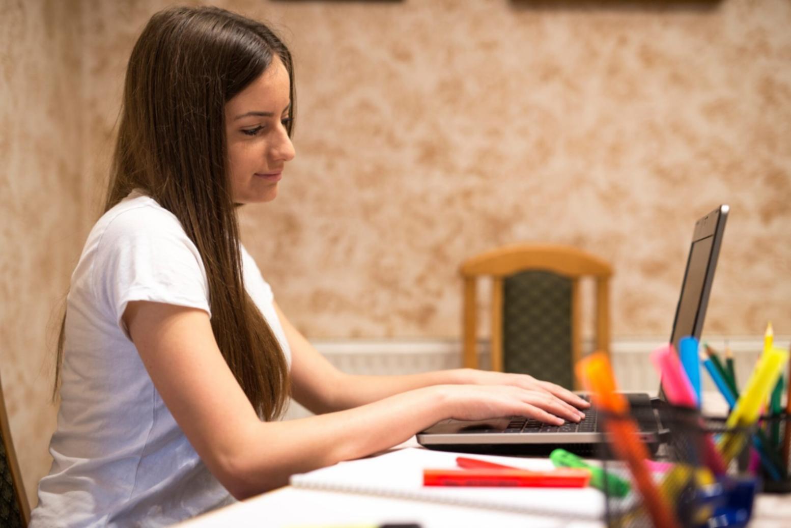 Financial professional analyzing competitor data on laptop with market research documents and coffee on desk